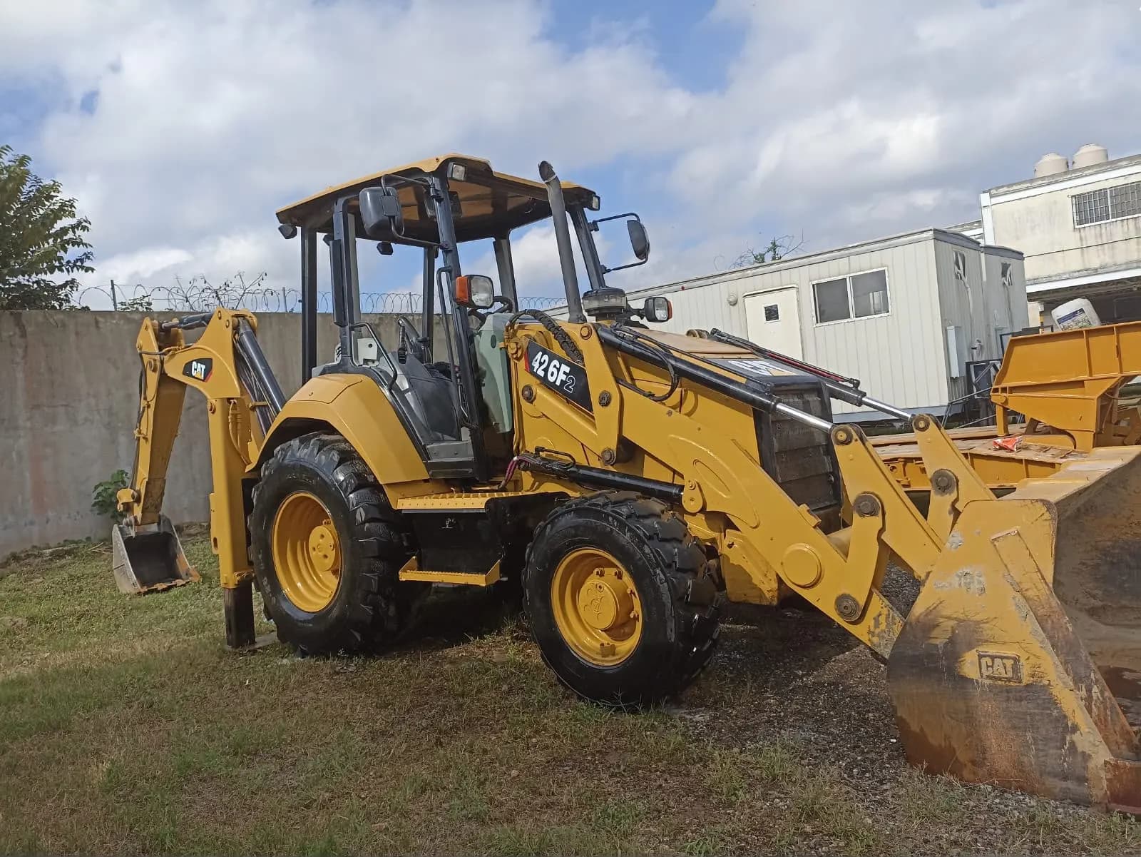 Retroexcavadora CAT 426F2 en patio, con cucharón de carga y brazo posterior.